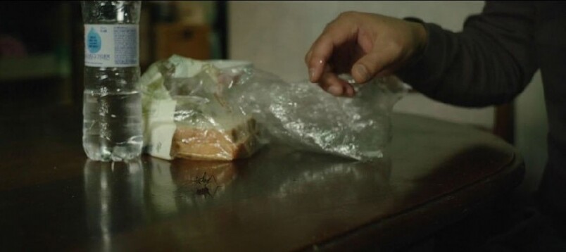 電影一開始,爸爸金基澤一邊吃麵包,一邊用手彈開一隻像蟋蟀般的昆蟲 電影一開始,爸爸金基澤一邊吃麵包,一邊用手彈開一隻像蟋蟀般的昆蟲